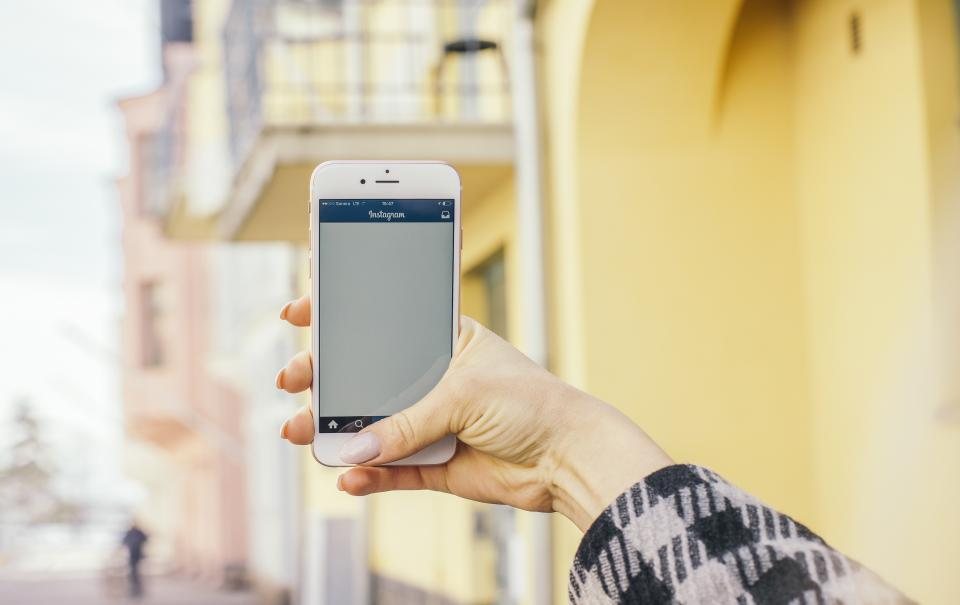 Hand holding a smartphone up to take a photo outdoors