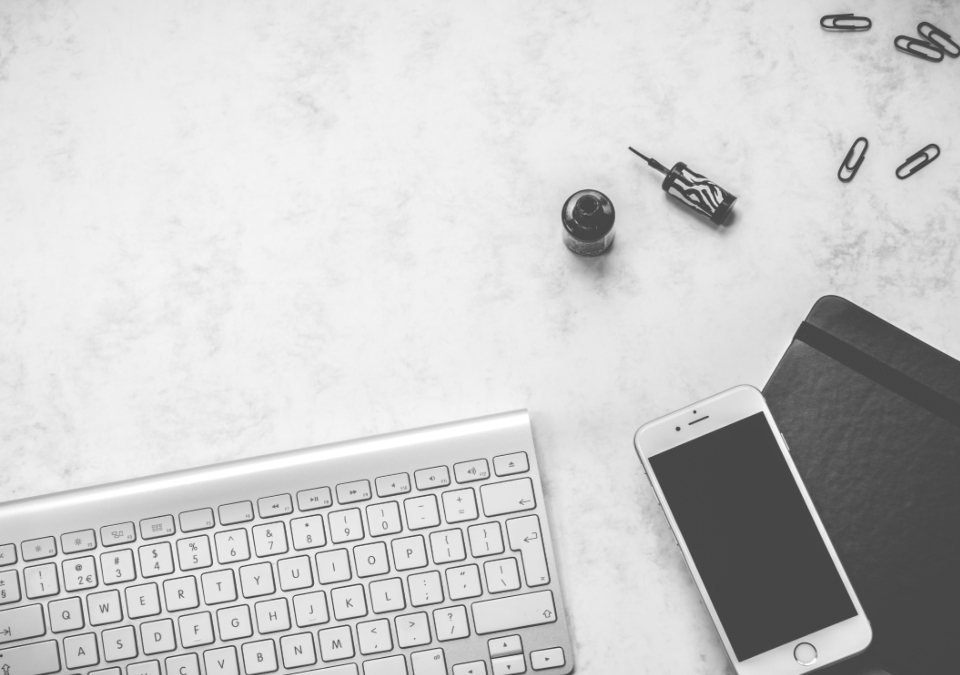 Keyboard, smartphone and notebook on a white desk